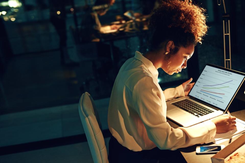 A person works on a laptop computer in a dimly lit office.