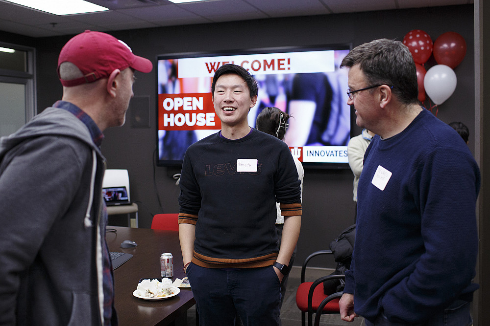 Three men talk in a conference room