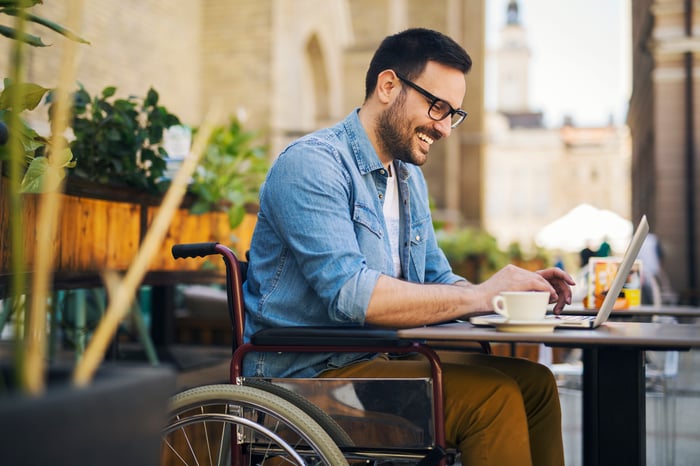 A person works on a laptop on a table outdoors.