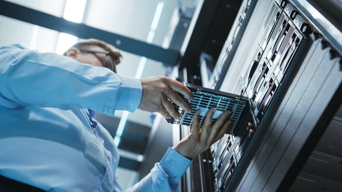 An engineer placing hard-disk drives into a data center server tower.