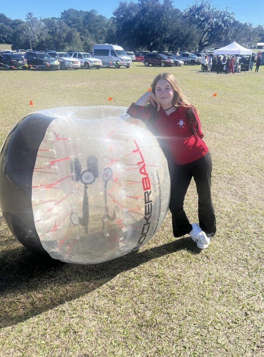 Angelina Depasquale, 11, co-owner of Ocala Knockerball, stands beside the inflatable bubble known as a knockerball. Participants don the knockerball over their upper body with their legs free, allowing them to collide with other players. (Courtesy of Christine Depasquale)