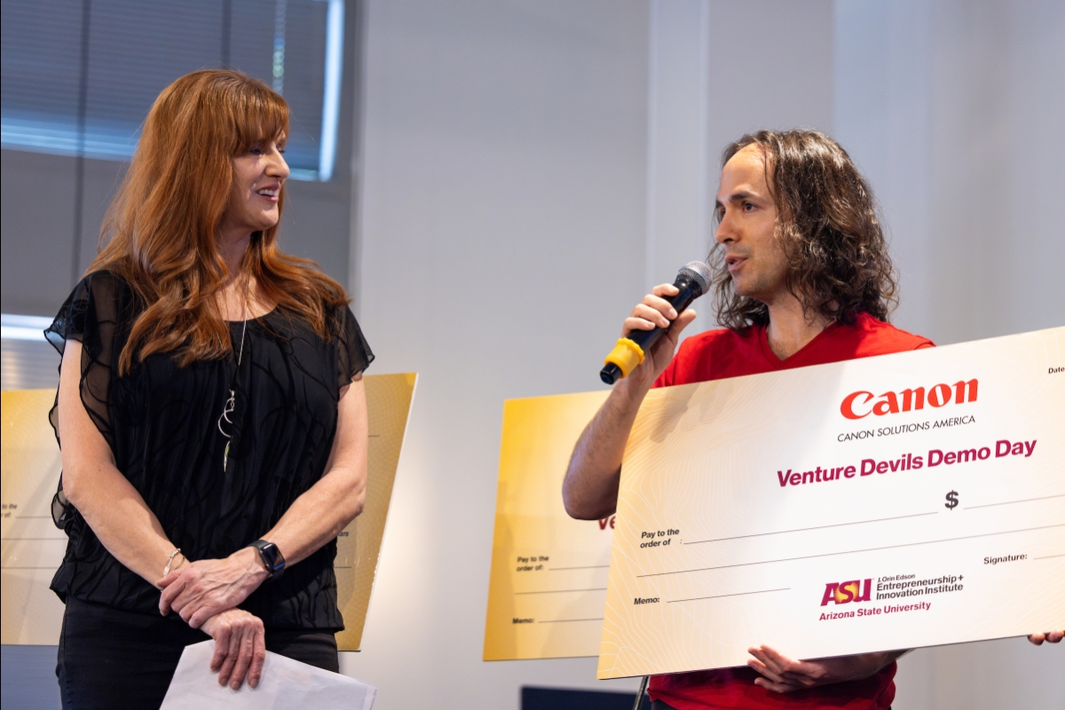 Man holding giant check speaking into microphone