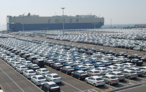 Cars sit in a parking lot before being placed on a ship and exported overseas