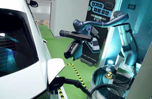 A collaborative robot adjusts its position to connect a charging cable to an electric vehicle charging port.