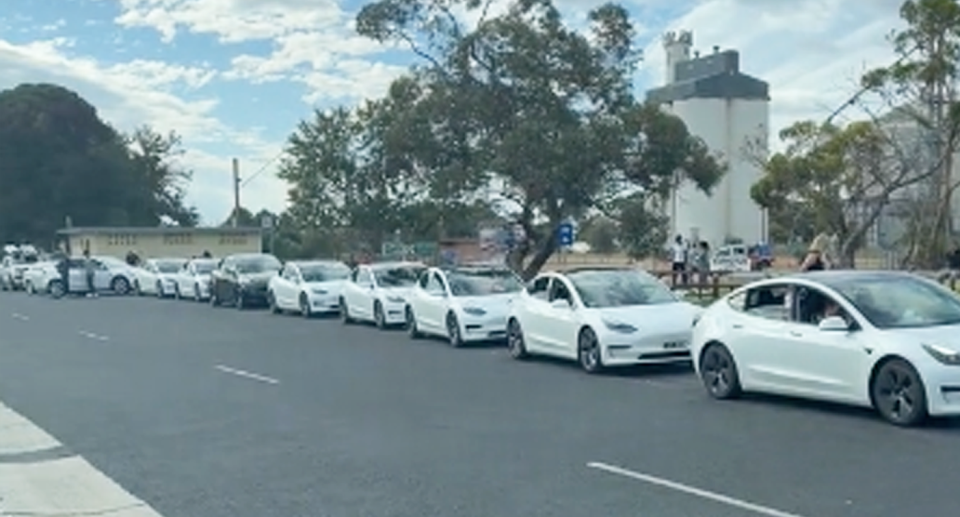 A long line of white electric vehicles queuing to use charging station in Keith, South Australia. 