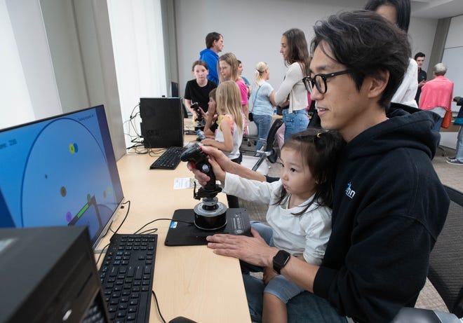 Senior research associate Beomyeong Park and his daughter Roha Park, 3, try out a psychomotor tool during the IHMC open house in Pensacola on Thursday, April 11, 2024.