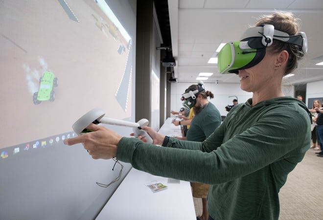 Teresa Hess, right, and others try virtual reality equipment during the IHMC open house in Pensacola on Thursday, April 11, 2024.