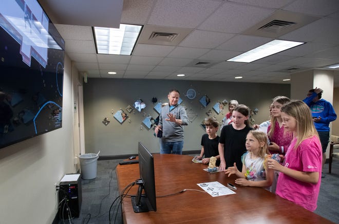 Researcher Larry Bunch, left, instructs the Trenka and Bobbitt children how to use hand motions to control a computer during the IHMC open house in Pensacola on Thursday, April 11, 2024.