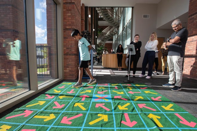 Tanay Kesharwani, of Pace, right, looks on as his son Srirama Kesharwani tries a Pensacola MESS Hall Archery Maze Challenge during the IHMC open house in Pensacola on Thursday, April 11, 2024.