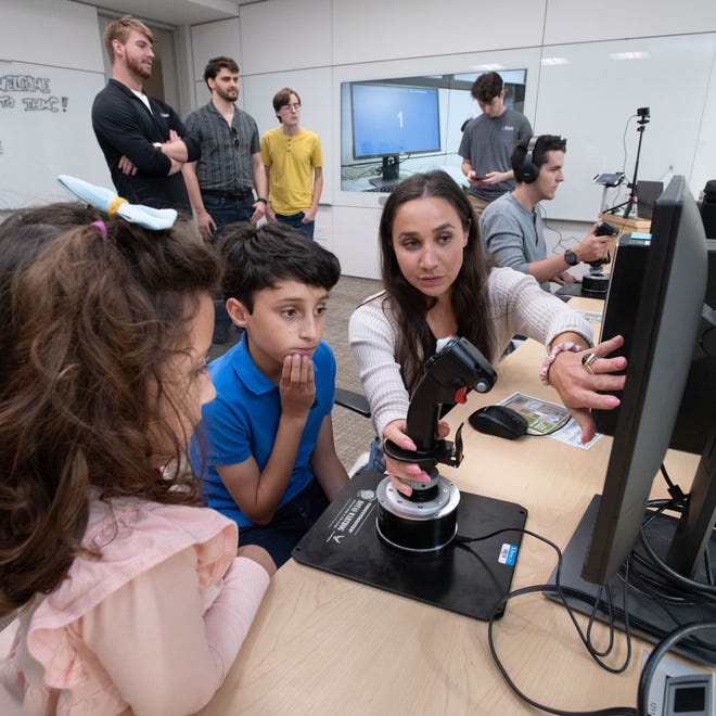 From right, research associate Emily Bowers helps Henrique Costa, 10, and Gabriela Costa, 6, try a psychomotor tool during the IHMC open house in Pensacola on Thursday, April 11, 2024.