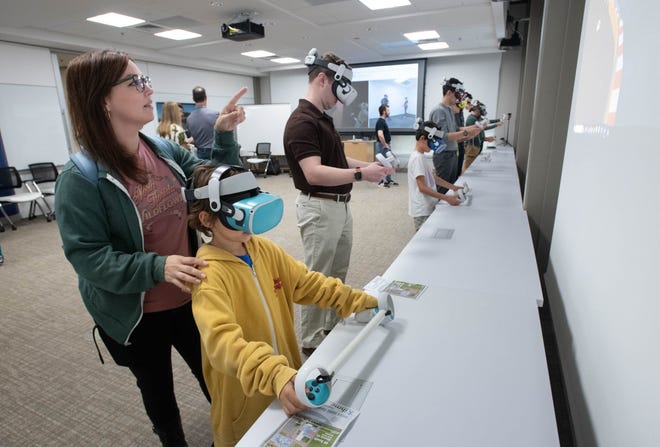 Meghan Colbert, left, of McDavid, helps her son Nathan Colbert, 6, as he tries virtual reality equipment during the IHMC open house in Pensacola on Thursday, April 11, 2024.