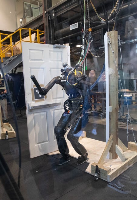 A robot named Nadia opens and walks through a door in the Robotics Lab during the IHMC open house in Pensacola on Thursday, April 11, 2024.