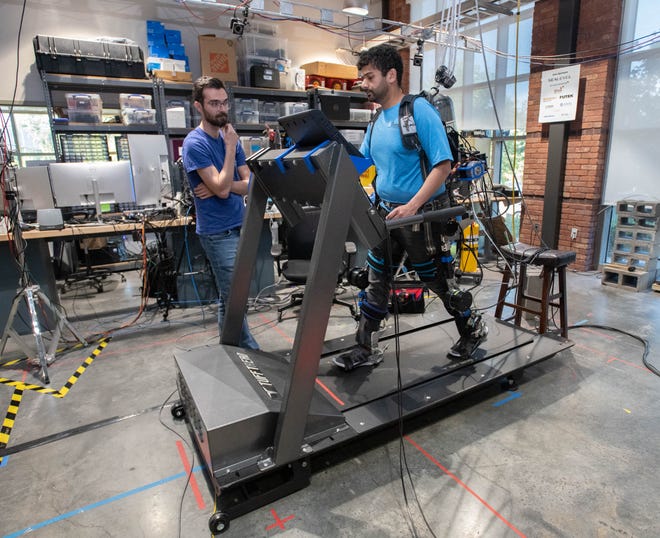 Controls engineer Owen Winship, left, looks on as Phd. student Chinmay Shah pilots an exoskeleton in the Robotics Lab during the IHMC open house in Pensacola on Thursday, April 11, 2024.