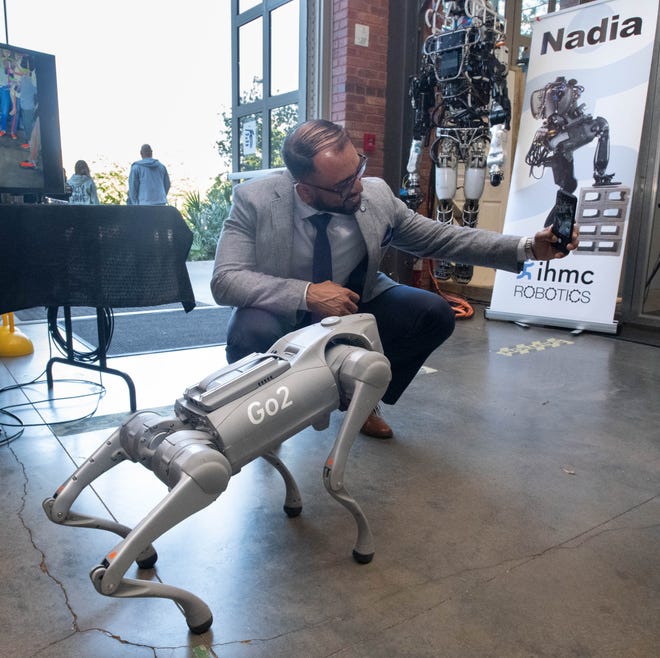 Nafees Alam takes a selfie with a robotic dog in the Robotics Lab during the IHMC open house in Pensacola on Thursday, April 11, 2024.