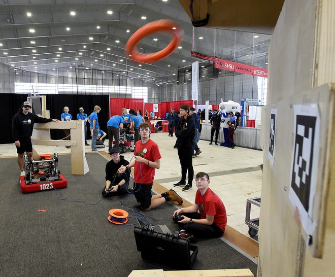 Ethan Bellino drive team coach (back left) watches the high school Bedford Express FRC Team #1023 robotics team members electronic lead and chassis driver Eric Koenemann, CAD lead Walker Schmus, drive team manipulator Ryan Marckel and looking on drive team technician Olivia Szczepanik practice the Crescendo High Note Toss on the practice field at the FIRST in Michigan State Championship 2024 at Saginaw Valley State University April 5, 2024.