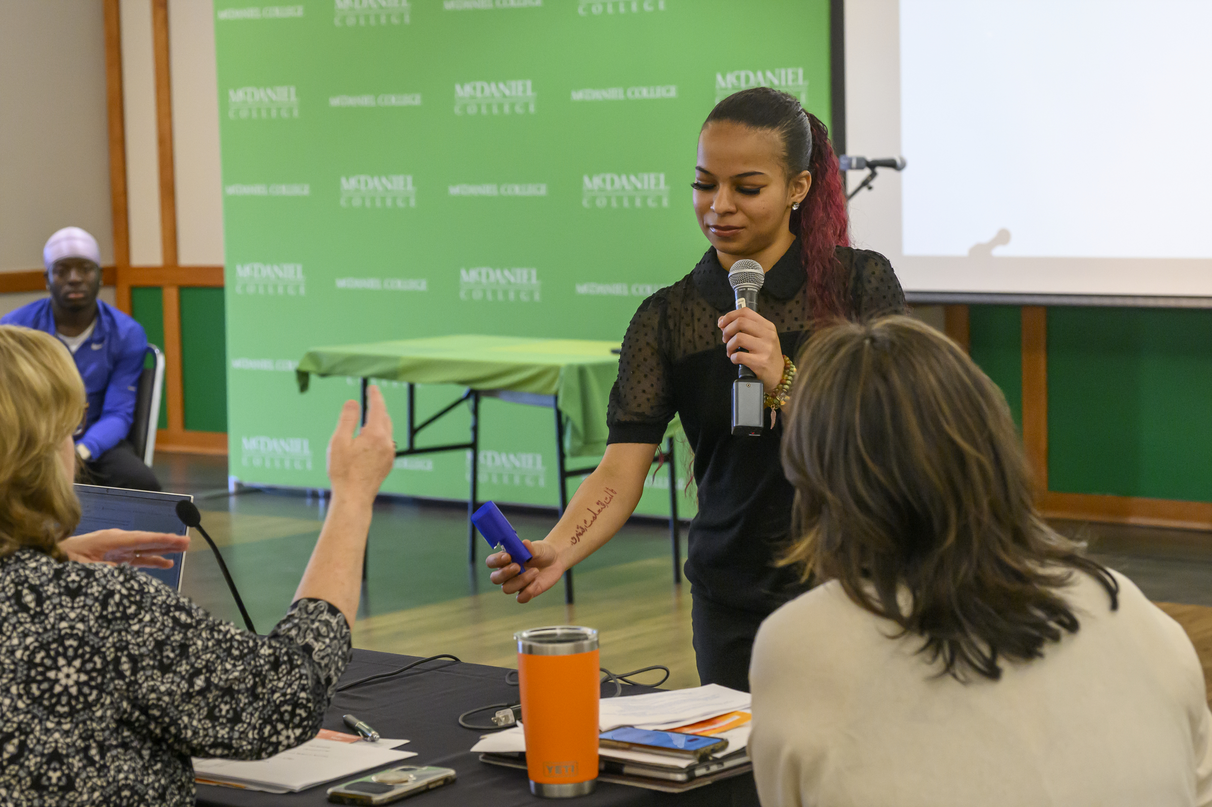 Lauren Dixon shows a judge a protype of her idea FyFence, a wind blocker for lighter flames, during the Innovation and Entrepreneurship Challenge at McDaniel College. (Thomas Walker/Freelance)