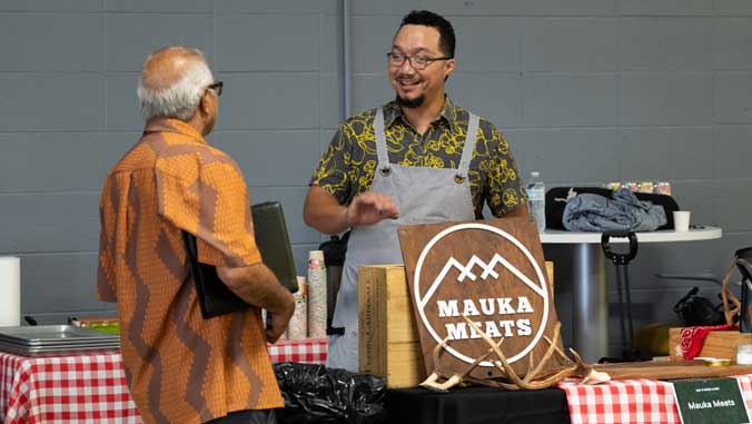 Mauka Meats vendor talks with visitor