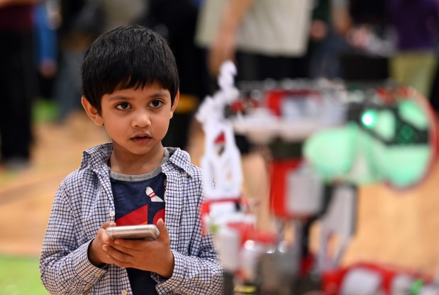 Showing concentration controlling a robot on right with a app on a cell phone is Arjun Babburi, 4, a preschooler from Long Grove at Maker Faire Lake County on April 13, 2024 at the College of Lake County In Grayslake.