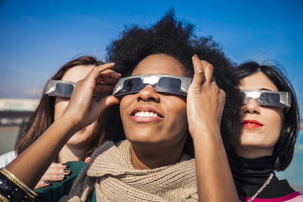 Woman wearing solar glasses looking up at the sky