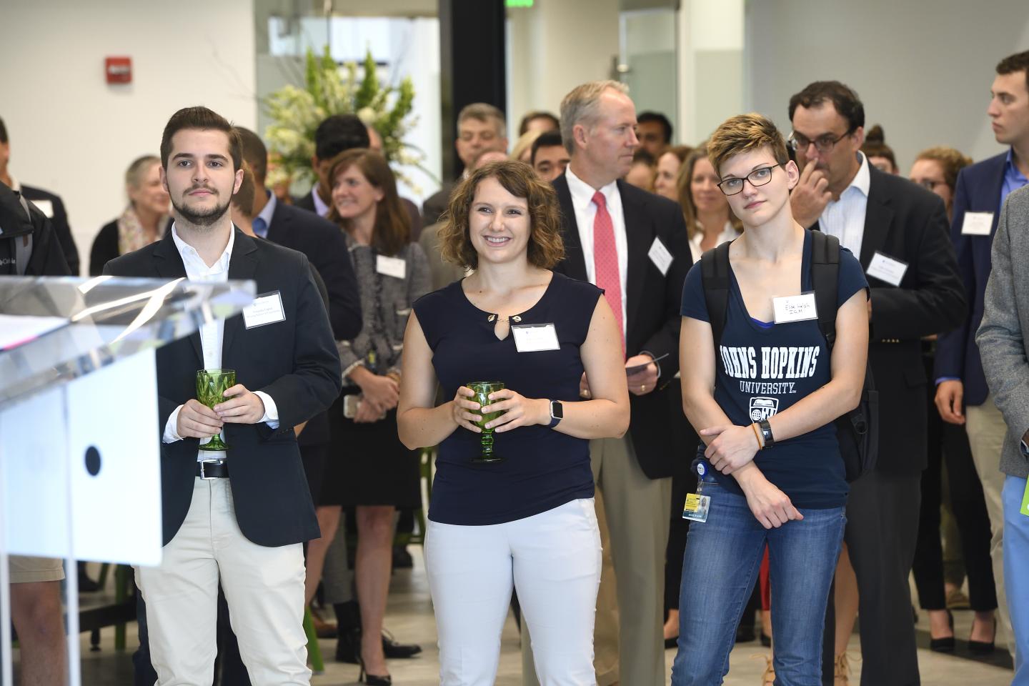 Pava LaPere stands smiling amongst a crowd in the Fastforward U building. She is holding a green goblet.