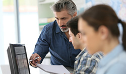 Two men and a woman having a meeting, looking at a monitor together