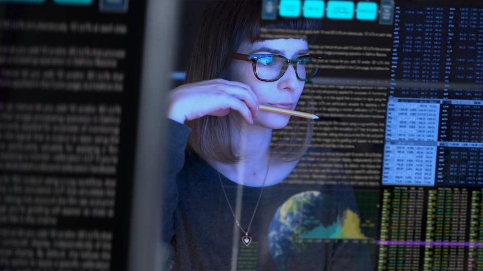 An IT worker analyzes data on a computer screen.