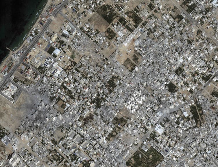 A satellite photo showing a built-up area in which. many buildings are damaged and destroyed.