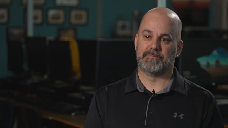 A bald man with a grey beard wearing a black Under Armour shirt