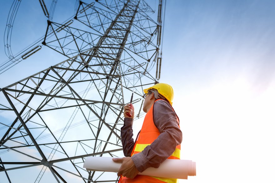 A worker standing at the bottom of a telecom tower.