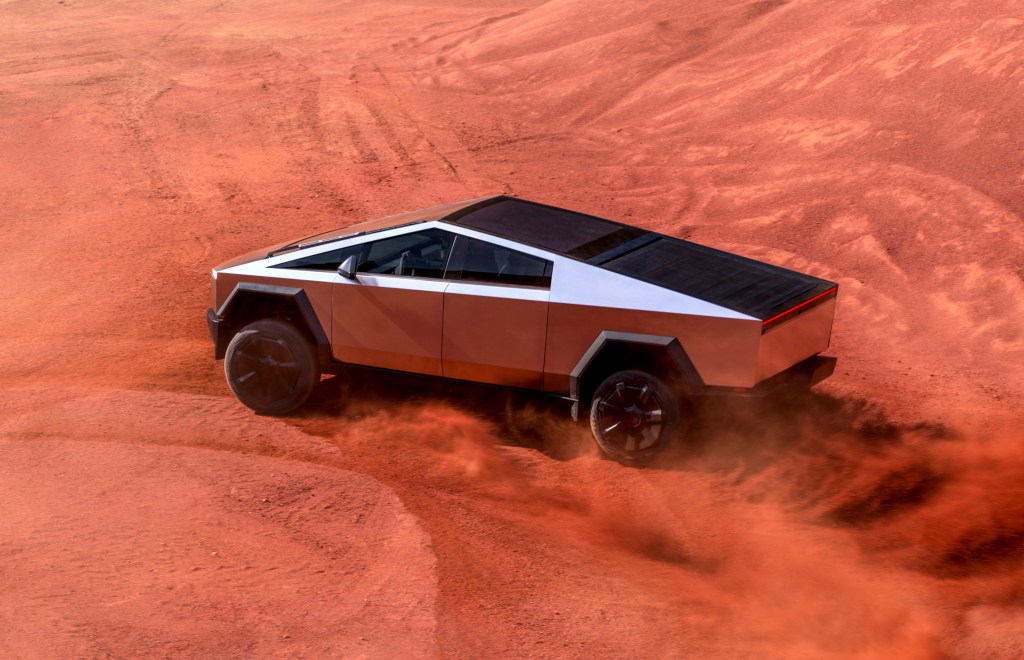 A Tesla Cybertruck doing donuts in the sand.