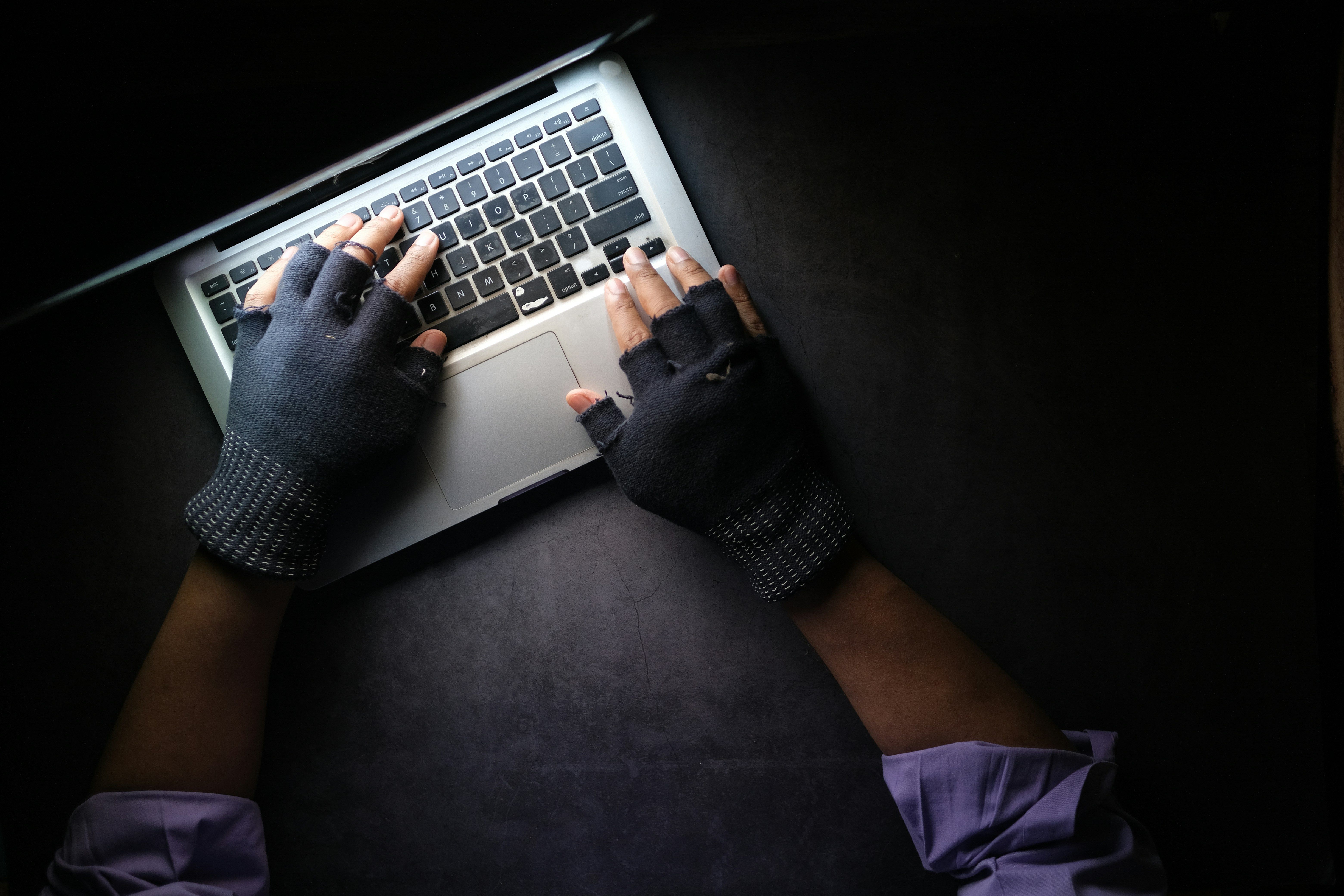 Image of a gloved criminal using a laptop.