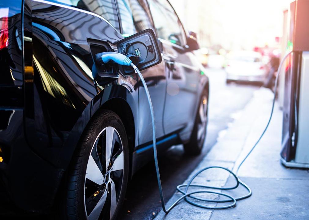 Black electric car plugged into charger.