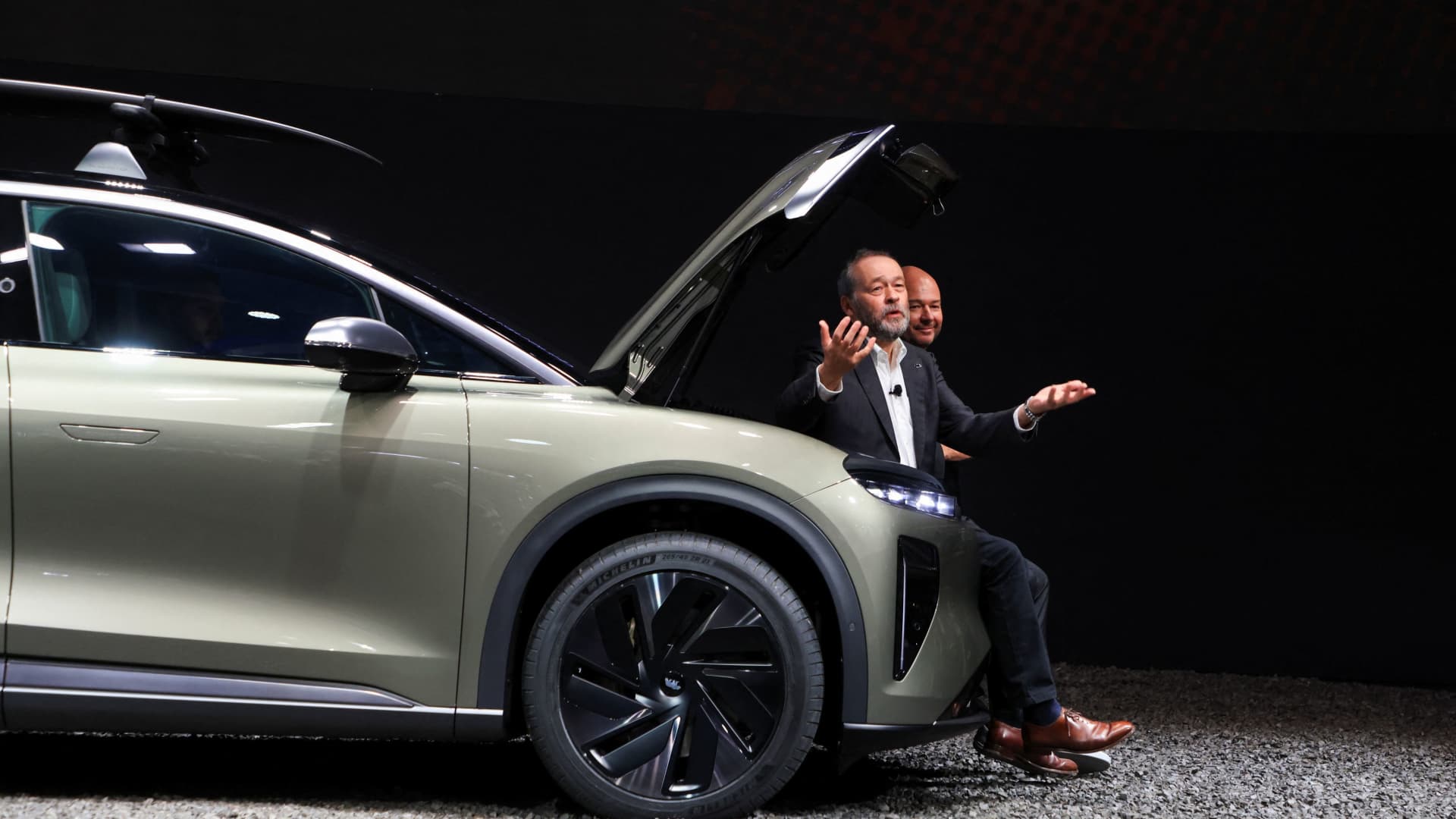 Lucid Group CEO Peter Rawlinson and Derek Jenkins, senior vice president of design and brand at Lucid Motors sit on frunk of Lucid’s Gravity electric SUV during the press day preview of the Los Angeles Auto Show in Los Angeles, California, U.S. November 16, 2023. 