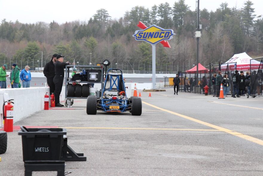 Students work on a computer near the race track at the New Hampshire Motor Speedway.