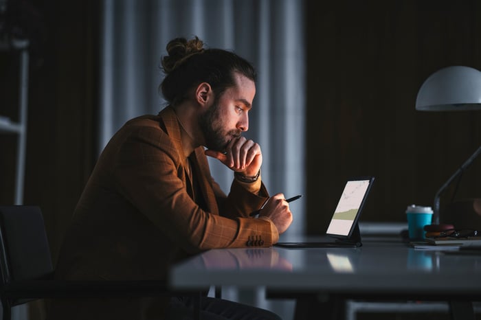 An investor works on a laptop in a darkened room.