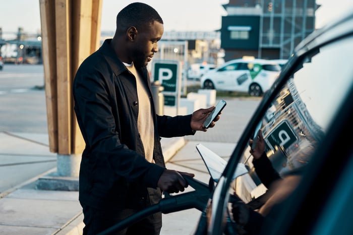 Person charging their electric vehicle while looking at a cell phone. 