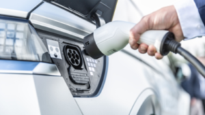 The driver of the electric car inserts the electrical connector to charge the batteries. Electric vehicle charger