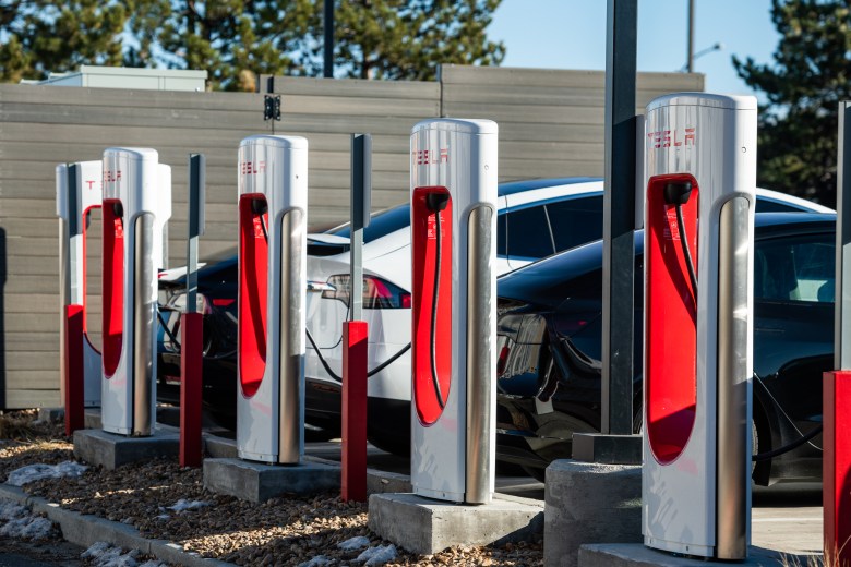 A row of Tesla Superchargers with cars plugged in.