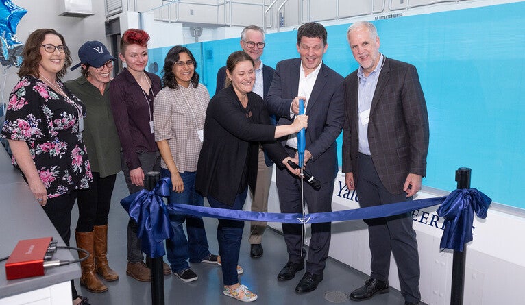 Group of people cutting a ribbon with large scissors.