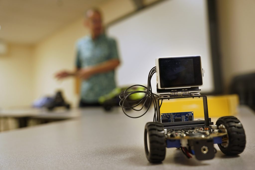 An electric vehicle which uses video to maneuver sits in front of Kūlia Academy interim executive director Andy Gokce Wednesday, April 24, 2024, in Honolulu. This tuition-free charter school specializing in AI and data since only accepts 100 sixth graders. (Kevin Fujii/Civil Beat/2024)