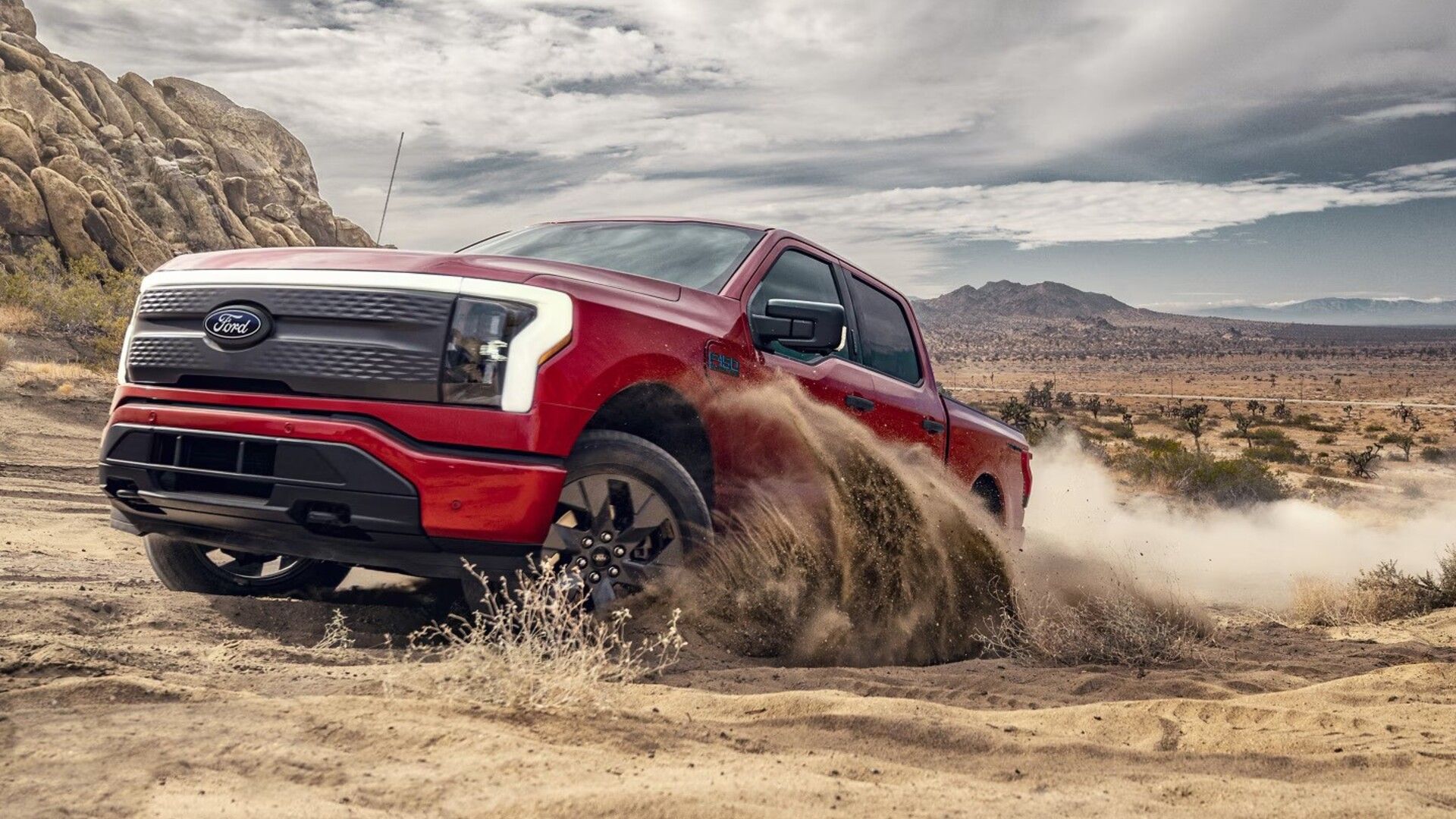 Red 2024 Ford F-150 Lightning 3/4 front view driving on sand