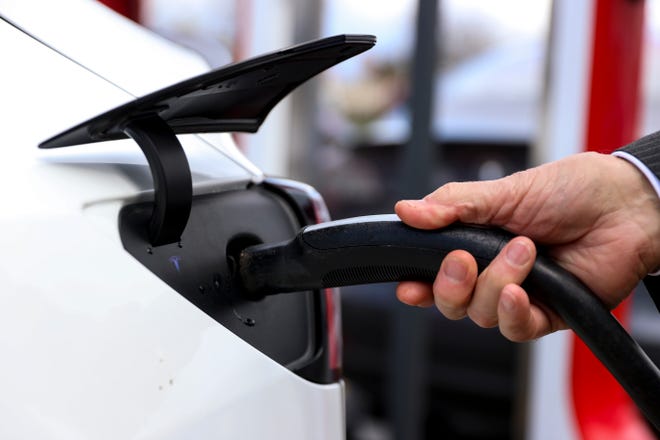 A Tesla driver plug in at an electric charging station.