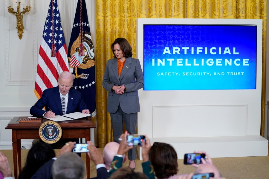 FILE - President Joe Biden signs an executive on artificial intelligence in the East Room of the White House, Oct. 30, 2023, in Washington. Vice President Kamala Harris looks on at right. The White House said Wednesday, Feb. 21, 2024, that it is seeking public comment on the risks and benefits of having an AI system's key components publicly available for anyone to use and modify. (AP Photo/Evan Vucci, File)