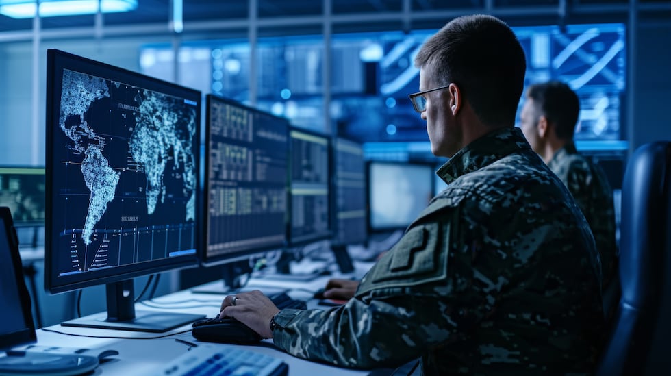 military personnel is focused on monitoring multiple computer screens in a high-tech...