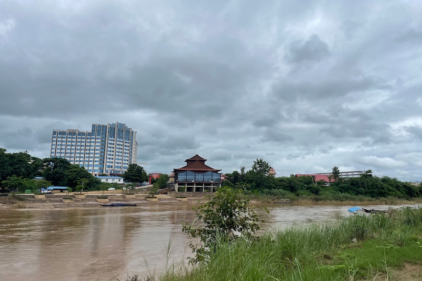 A blue Chinese-style multistory building in the background with a river in the foreground. 