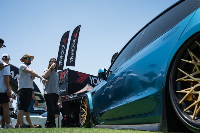 Visitors stop to check out a customized 2017 Tesla Model 3 on display at the Electrify Expo outside State Farm Stadium on May 4, 2024 in Glendale, Ariz.