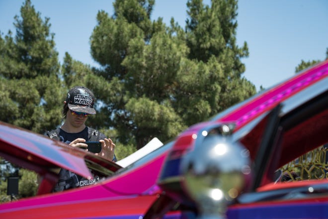 Matt Jones records a video on his phone of the customized electric vehicles display at the Electrify Expo outside State Farm Stadium on May 4, 2024 in Glendale, Ariz.