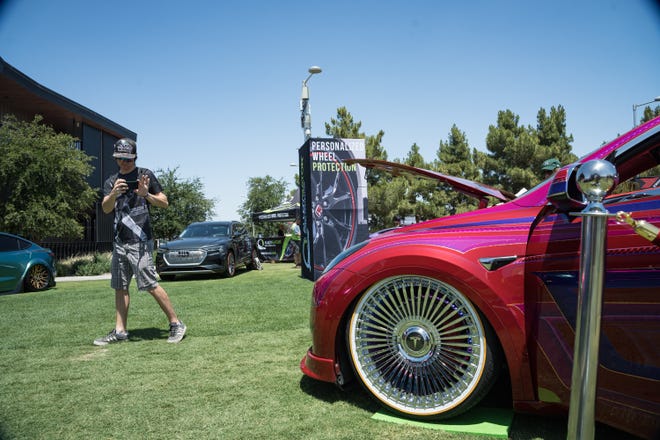 Matt Jones records a video on his phone of the customized electric vehicles display at the Electrify Expo outside State Farm Stadium on May 4, 2024 in Glendale, Ariz.