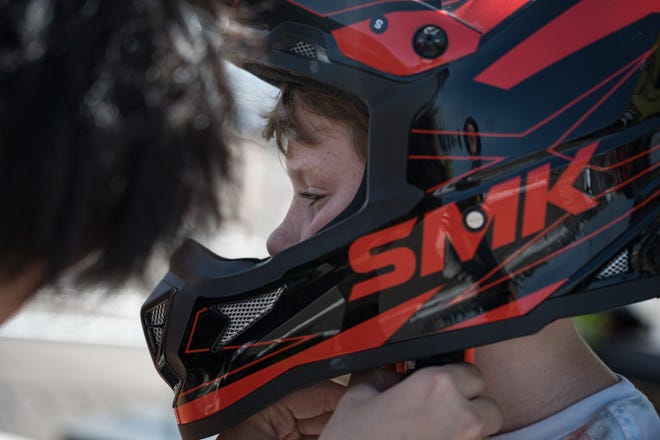 Levi Carmichael, 9, puts on a helmet as he prepares to try the Rawrr Mantis Mini electric bike for kids at the Electrify Expo outside State Farm Stadium on May 4, 2024 in Glendale, Ariz.