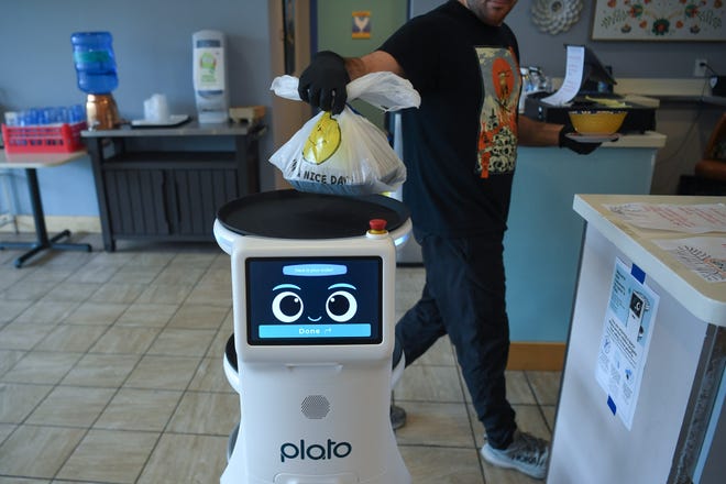 Owner Nathan grabs a carryout order from Rosie the robot at Fai Thai in Knoxville, Thursday, May 23, 2024.